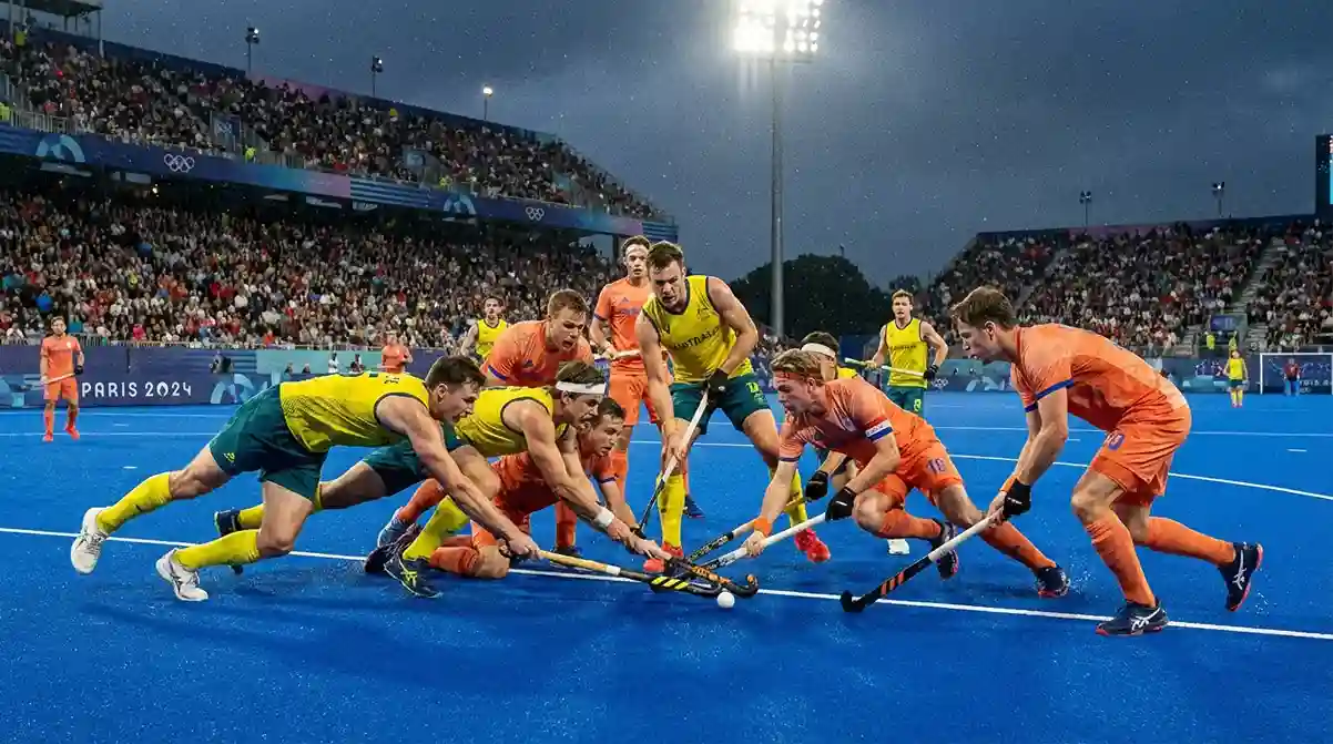 Hockeyspelers in actie tijdens een olympische wedstrijd met de olympische ringen op de achtergrond